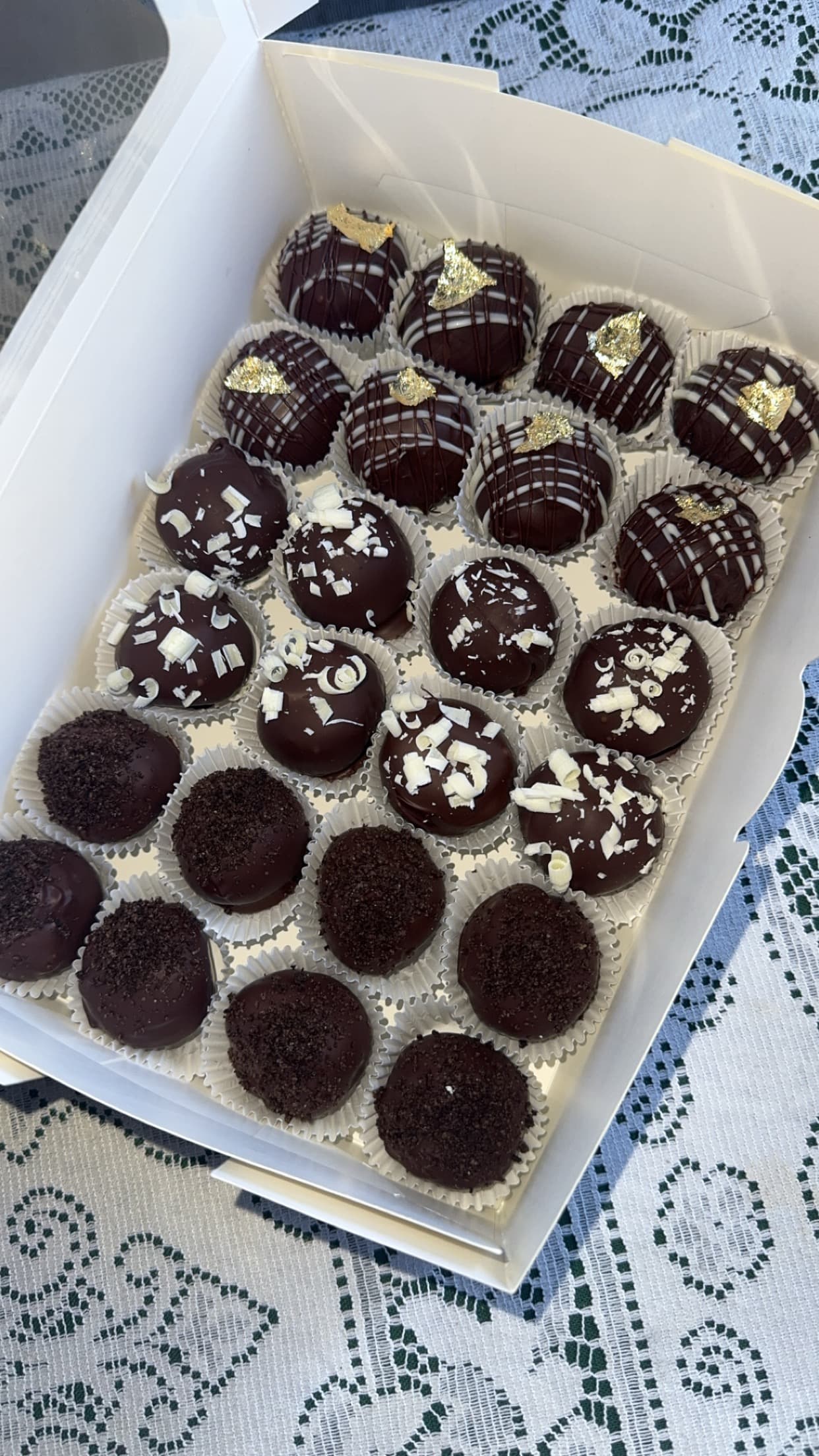 Tray of chocolate-coated sandwich-cookie truffles with white drizzle and sprinkles